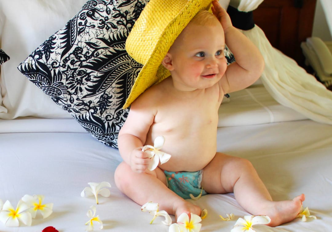Baby on hotel bed with hat