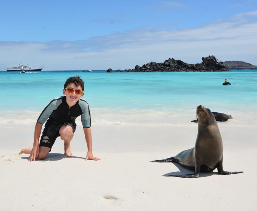 Boy in the Galapagos next to a seal