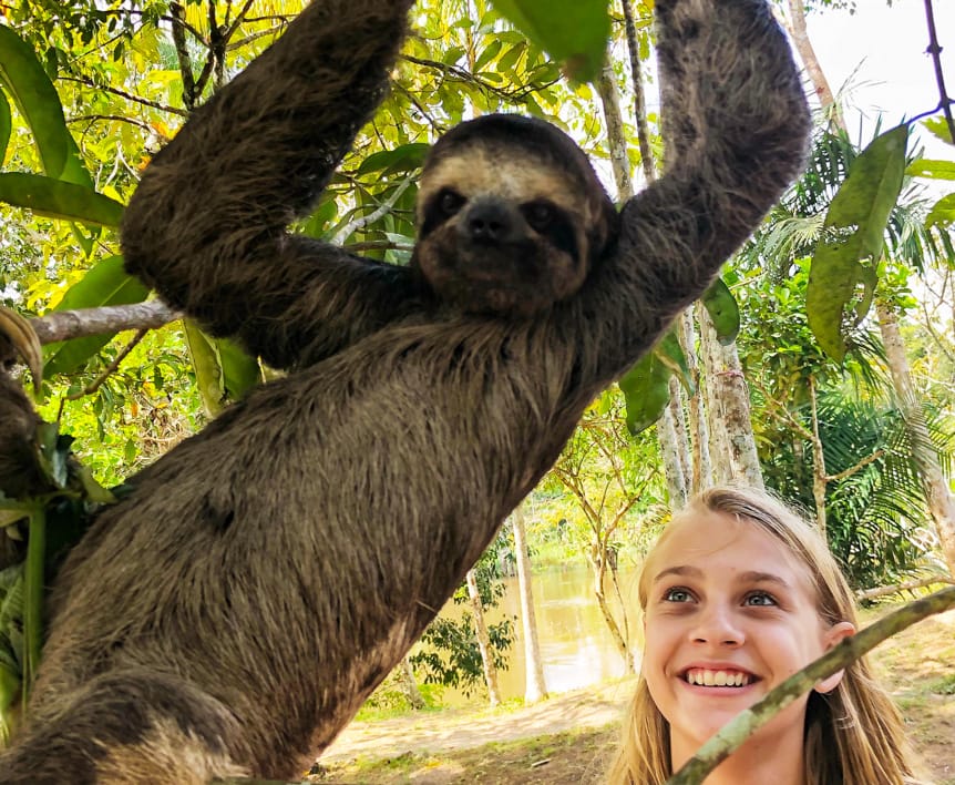Teen standing next to a sloth
