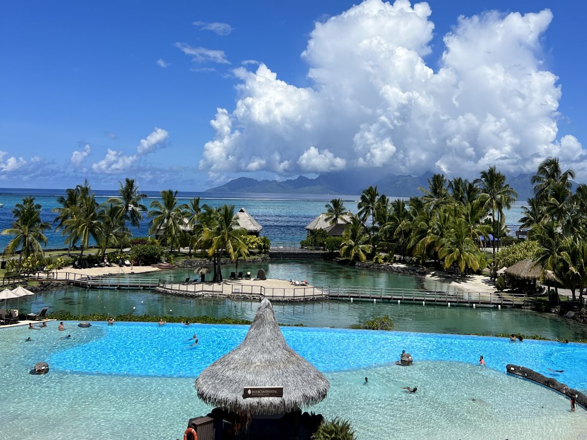 View of InterContinental Tahiti Resort and Spa pool, lagoon, and overwater Bungalows with Moorea in distance